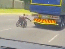 Man in wheelchair catches ride behind semi
