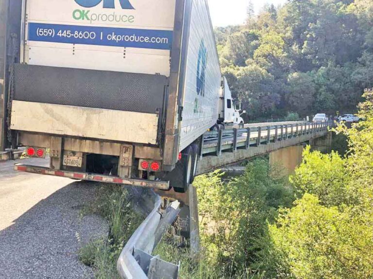 Produce truck’s trailer straddles guardrail, temporarily closes bridge