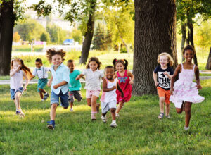 a group of preschoolers running on the grass in the Park