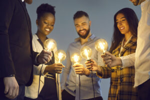 Diverse business team joining shining light bulbs as metaphor for sharing creative ideas