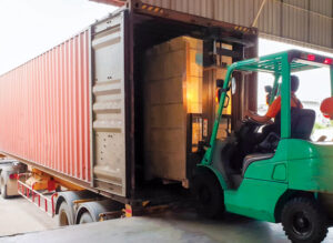 Forklift driver loading goods pallet into the truck container, freight industry warehouse logistics and transport