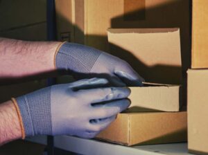 A man in gloves steals goods from a box in a warehouse. Problems with theft and security in the office