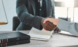 Lawyer, office and shaking hands for success in meeting, partnership and agreement or deal at a law firm. Professional attorney, notary and clients handshake for thank you, onboarding or consultation