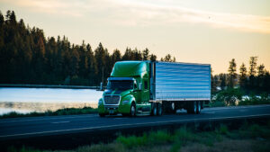 Long haul semi truck driving along a scenic stretch of freeway.
