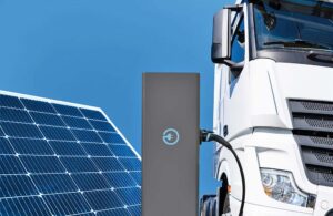 Electric truck with charging station on a background of solar panels.