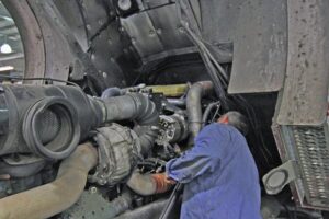 Mechanic working on engine, coe truck