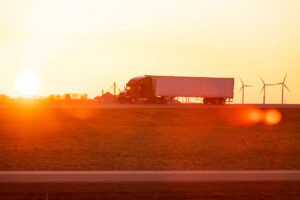 Semi truck on the road while sunset. wind turbines background