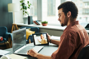 Side view of young student reading grammar rules on laptop screen
