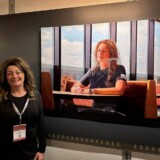 Professional driver Carol Nixon, one of the 40 "Sisters of the Road," poses with her photograph in the touring exhibit. (Courtesy: Anne-Marie Michel Photography)