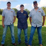 Wade Burcham (left) and brother Tyrone Burcham (right) attribute their love of the trucking industry and dedication to safety to their father, Tyrone Burcham Sr. (center). (Courtesy: Estes)